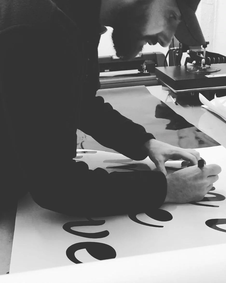 Weeding surplus vinyl from a cut graphic on a bench
